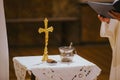 Closeup of the cross on the table with a priest next to it during a wedding celebration Royalty Free Stock Photo
