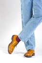 Closeup of Crossed Mens Legs in Brown Oxford Brogue Shoes. Posing in Blue Jeans Against White Background Royalty Free Stock Photo