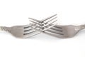 Closeup of the crossed tines of two forks. White background selective focus