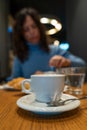 closeup of a cup of cappuccino and a beautiful blurry middle aged woman having breakfast in the background - travel and vacation Royalty Free Stock Photo