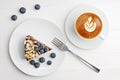 Closeup cup of coffee cappuccino and piece of homemade chocolate cheesecake with blueberries and almond slices on white wooden tab