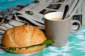 Closeup of a cup of coffee with a sandwich against newspapers