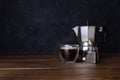 Closeup of a cup of espresso coffee and a Moka pot on the wooden table