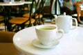 Closeup a cup of green tea and teapot on white round table in a tearoom Royalty Free Stock Photo