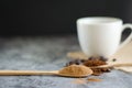 Closeup cup of hot coffee and ground coffee on wooden spoon.