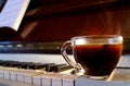 Closeup a Cup of Hot Coffee with Smoke on the Piano with Blurry Music Sheet Royalty Free Stock Photo