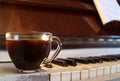 Cup of Hot Coffee with Smoke on the Piano with Blurry Music Sheet Royalty Free Stock Photo