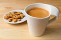 Cup of hot frothy coffee with plate of cookies on wooden table Royalty Free Stock Photo