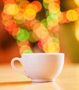 Closeup of a cup isolated against a vibrant bokeh background. One white teacup on a table. Crockery used to enjoy a warm