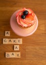 Closeup of cupcake with chocolate frosting and cinder toffee with letters "A cake day" on the table Royalty Free Stock Photo