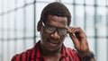 Closeup curious african man with adjusting his glasses for better vision, trying to peep secrets, spying. Royalty Free Stock Photo