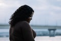 Closeup curly laughing African American interracial shy dark-haired woman looking down near bridge, river. Copy space