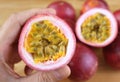 Closeup of Cut Fresh Ripe Passion Fruit in Hand with Blurry Pile of Whole Fruits In the Backdrop