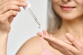 Closeup cut shot of mature Asian woman putting pipette serum essence in hand.