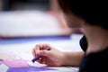 Closeup cute Asian girl is using chalk paint on large piece of paper. Side view of child doing art on table. Royalty Free Stock Photo