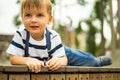 Closeup cute baby boy lying on wooden bench at amusement park relaxing summer vacation Royalty Free Stock Photo