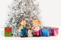 cute boy and girl dolls with a puppy and small gift boxes stacked under the Christmas tree Royalty Free Stock Photo