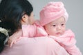 Closeup cute child care with mother indoor. Happy little toddler baby girl smiling lying on bed on white sheet at home looking at Royalty Free Stock Photo