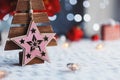 Closeup cute Christmas pink star on wooden fir indoor with red home festive decor and blurred bokeh background in daylight Royalty Free Stock Photo