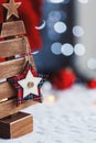 Closeup cute Christmas star with button on wooden fir indoor with red home festive decor and blurred bokeh background in daylight Royalty Free Stock Photo