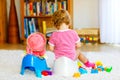 Closeup of cute little 12 months old toddler baby girl child sitting on potty. Kid playing with doll toy. Toilet Royalty Free Stock Photo