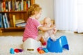 Closeup of cute little 12 months old toddler baby girl child sitting on potty. Kid playing with doll toy. Toilet Royalty Free Stock Photo