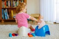 Closeup of cute little 12 months old toddler baby girl child sitting on potty. Kid playing with doll toy. Toilet Royalty Free Stock Photo