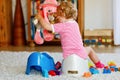 Closeup of cute little 12 months old toddler baby girl child sitting on potty. Kid playing with doll toy. Toilet Royalty Free Stock Photo