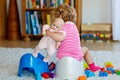 Closeup of cute little 12 months old toddler baby girl child sitting on potty. Kid playing with doll toy. Toilet Royalty Free Stock Photo