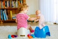 Closeup of cute little 12 months old toddler baby girl child sitting on potty. Kid playing with doll toy. Toilet Royalty Free Stock Photo