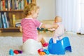 Closeup of cute little 12 months old toddler baby girl child sitting on potty. Kid playing with doll toy. Toilet Royalty Free Stock Photo