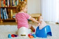 Closeup of cute little 12 months old toddler baby girl child sitting on potty. Kid playing with doll toy. Toilet Royalty Free Stock Photo