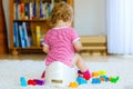 Closeup of cute little 12 months old toddler baby girl child sitting on potty. Kid playing with educational wooden toy Royalty Free Stock Photo