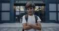 Closeup cute school boy standing with hands crossed. Pupil posing on schoolyard. Royalty Free Stock Photo