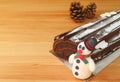 Closeup a Cute Snowman Marzipan of Christmas Roll Cake on Wooden Table with Blurry Dry Pine Cones in Background Royalty Free Stock Photo