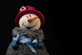Closeup of a cute stuffed snowman with a red hat for Christmas isolated on a dark background