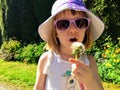 A closeup of cute 5 year old girl holding and blowing on a dandelion in a garden.  She is wearing a unicorn shirt Royalty Free Stock Photo