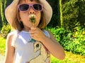 A closeup of cute 5 year old girl holding and blowing on a dandelion in a garden.  She is wearing a unicorn shirt Royalty Free Stock Photo