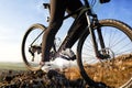 Closeup of cyclist man legs riding mountain bike on outdoor trail on hill