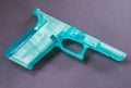 Closeup of 3D printed turquoise "Ghost Gun" on a dark background.