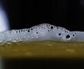A closeup of dark beer in a cup with bubble suds at the top, foam formed on top of a alcoholic beverage Royalty Free Stock Photo