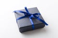 Closeup of dark blue gift box and shiny blue ribbon, bow on the white surface Royalty Free Stock Photo