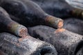 Closeup dark dusty wine bottles with old crumbly cork. Long aging, musty winery vault, rare ancient collection, cork