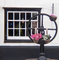 Closeup of a decorative iron steering wheel with hanging potted flowering plants