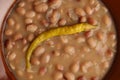 Closeup of the delicious bean soup with a spicy pepper in a brown bowl