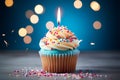 Closeup delicious birthday cupcake with burning candle on blue