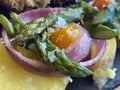 Closeup of delicious colourful presentation.Asparagus with red onion , small tomatoes and baked potatoes. Flake salted