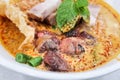 Closeup of delicious curry mee or curry laksa with fresh raw cockerel and roast pork