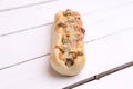 Closeup of a delicious hot dog with melted cheese and pepper on a wooden table