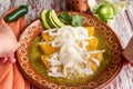 Closeup of delicious Mexican green enchiladas with sour cream and cheese, in a red patterned bowl